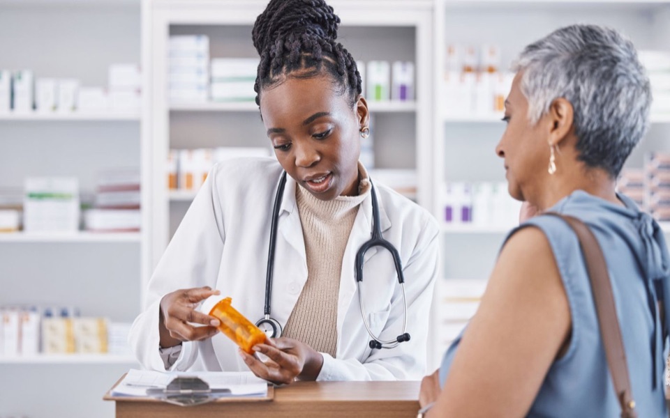 Pharmacist explaining a prescription bottle to an older customer